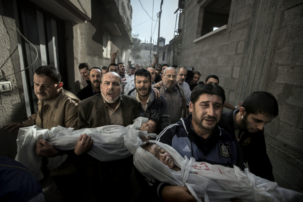 2013: Familiares cargan los cuerpos de dos niños muertos a causa de un ataque aéreo israelí a su casa en la Franja de Gaza. Foto: Paul Hansen.