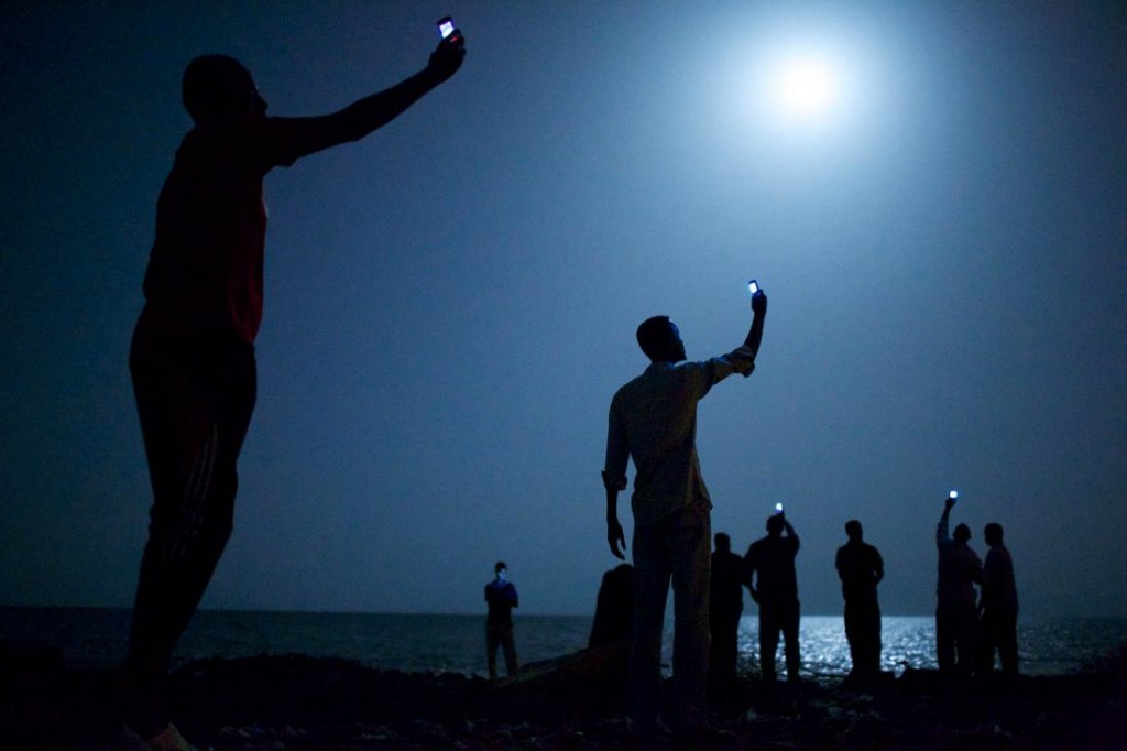 2014: Un grupo de migrantes africanos busca cobertura telefónica a las costas de Djibouti. Foto: John Stanmeyer. 